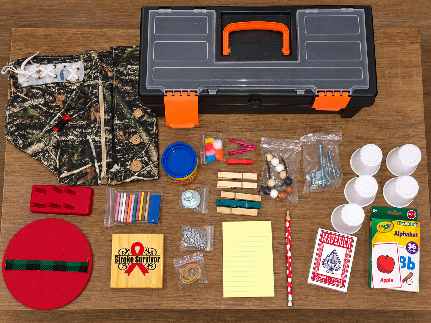 Fine motor kit laid out on a table with handmade wooden pieces, dressing panel, containers, clothespins, small objects, and carrying case
